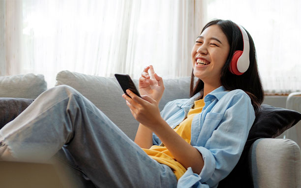 Garota sorridente usando fones de ouvido, aproveita as vantagens dos aplicativos gratuitos.